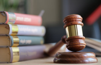 wooden judge gavel and stack of legal book on table